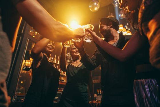 A group of people are toasting with beer glasses in a bar.