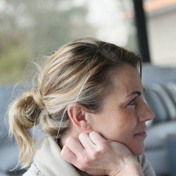 Woman adjusting her hair near a window, side profile in soft light