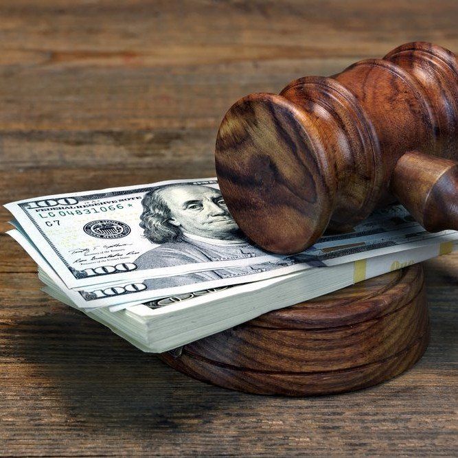 Gavel resting on a stack of U.S. dollar bills on a wooden table
