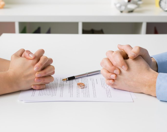 Couple sitting across from each other about to sign divorce papers