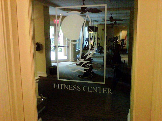 Glass door to a fitness center, white logo, and 