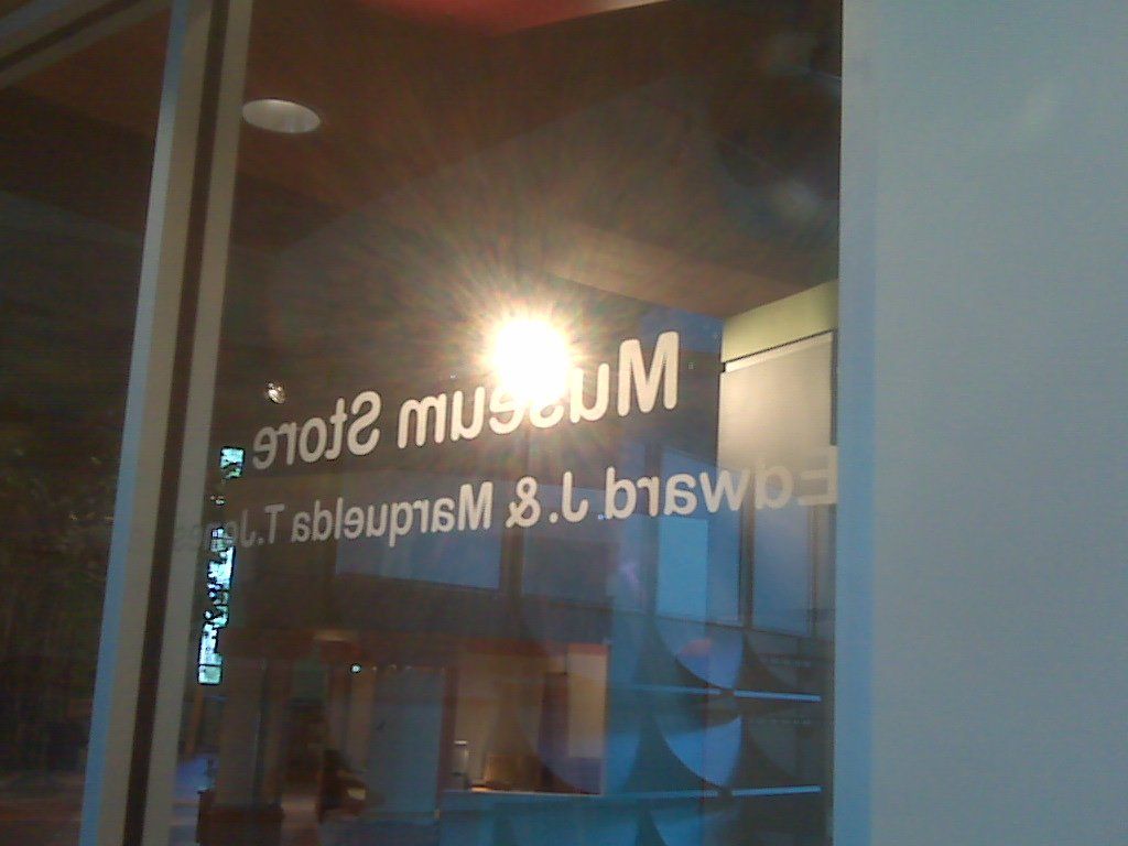 Museum store window with reflective light, lettering visible.