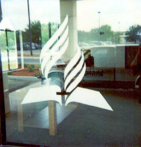 White Seventh-day Adventist church logo on a glass door; a Bible with a flame and a cross.