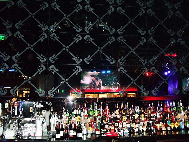 Bar with a wall of guitar-shaped mirrors, and a large selection of liquor bottles.