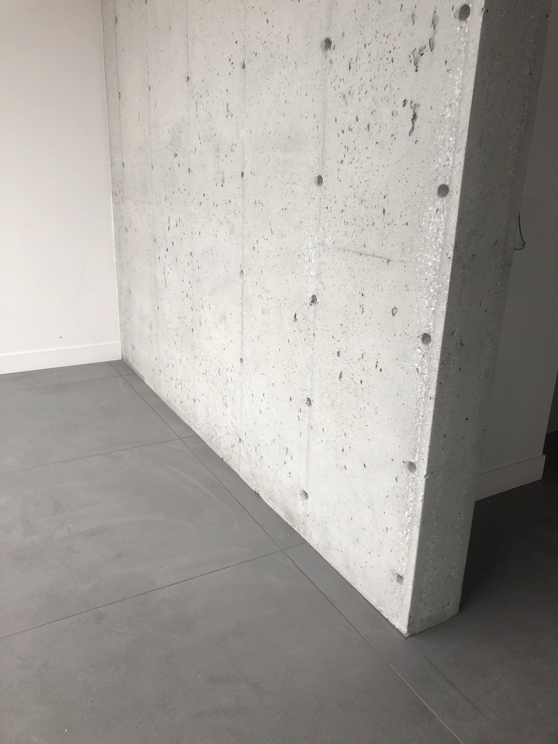 Concrete wall corner with gray flooring.
