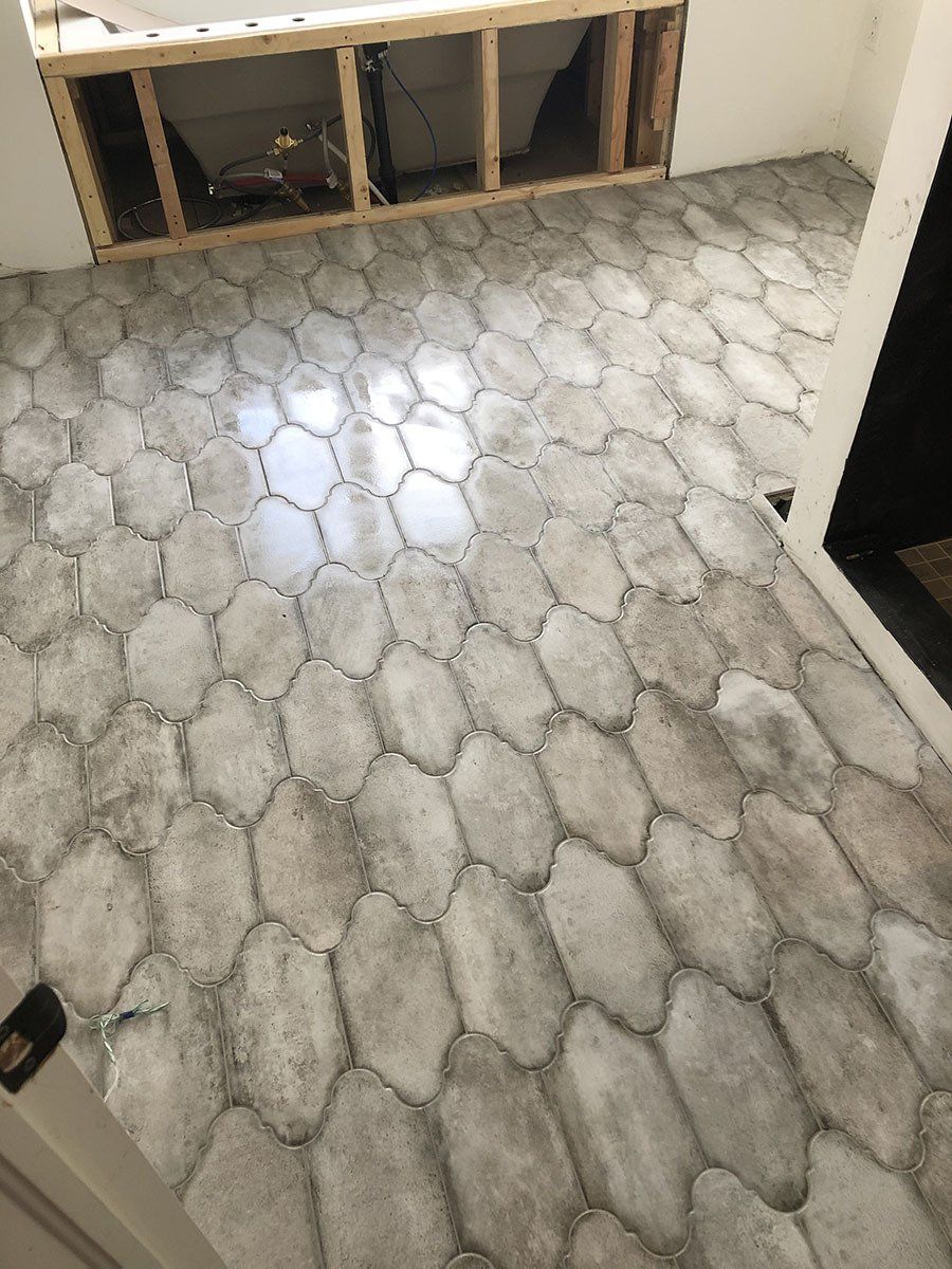 Stone-like tile floor with irregular, oval-shaped tiles. Wooden cabinet framing above the floor.