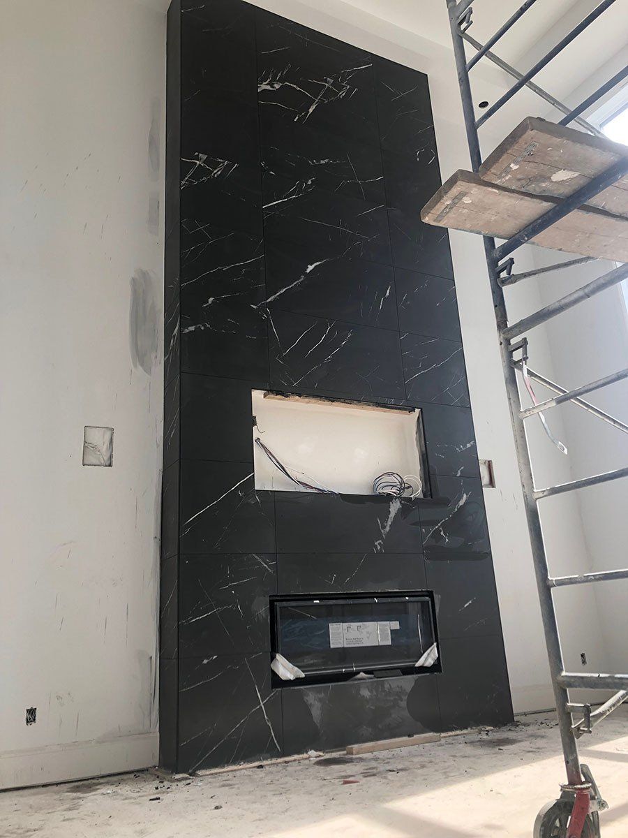 Cheminée en marbre noir en cours d'installation ; chantier inachevé ; échafaudages à proximité.