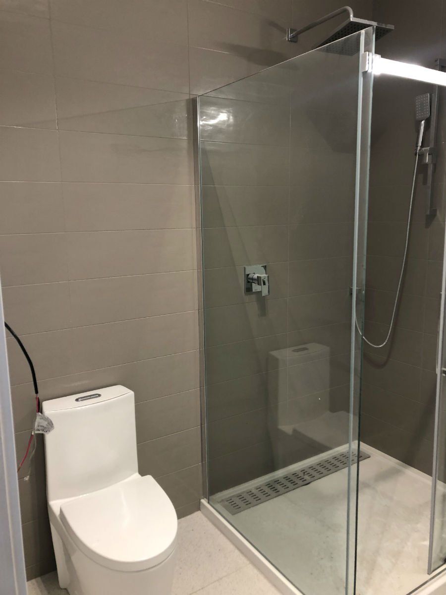 Bathroom with a toilet, glass shower, and gray walls.