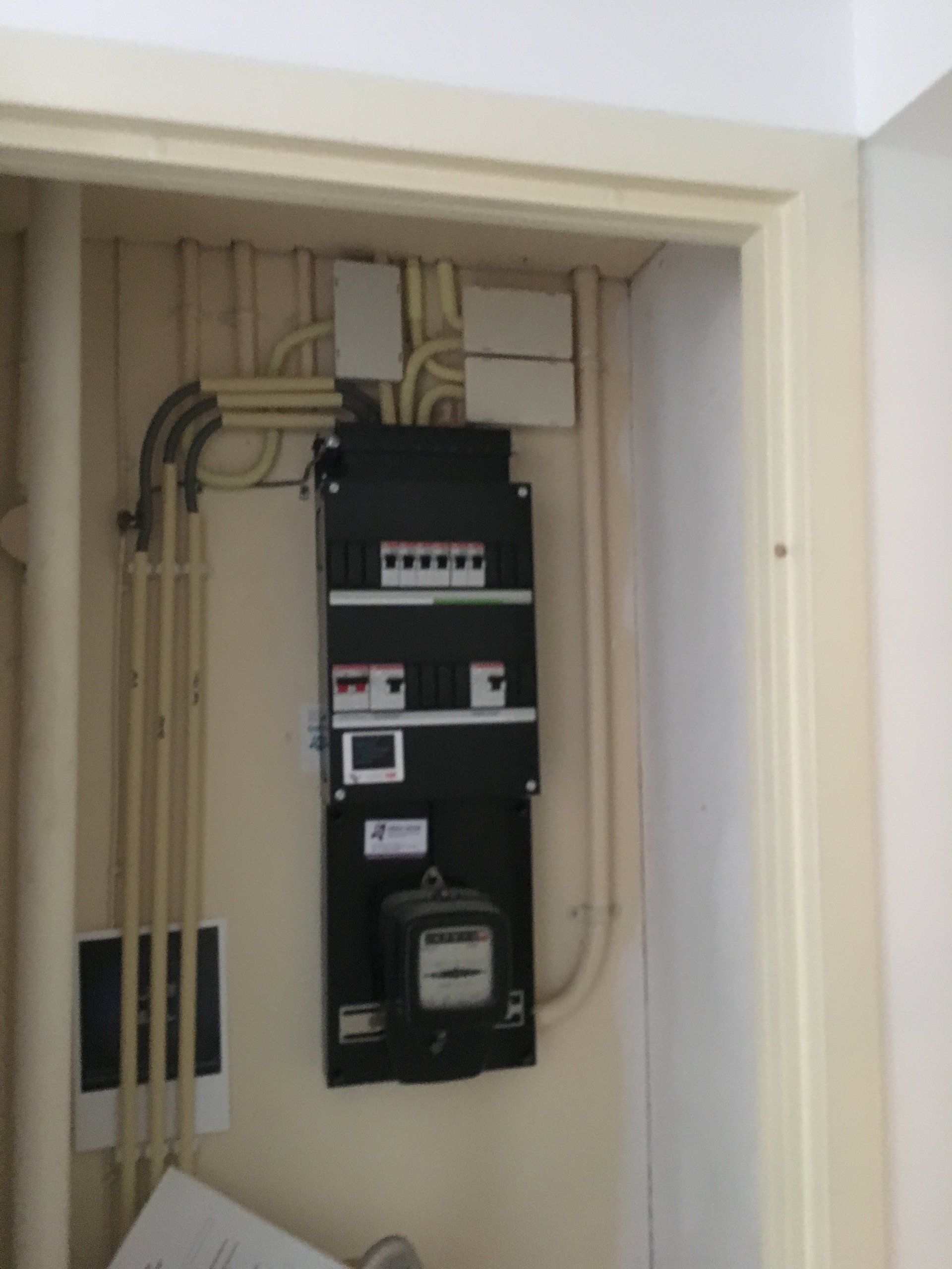 Elektrische verdeelkast in een muuruitsparing met zichtbare bedrading en meterkast.