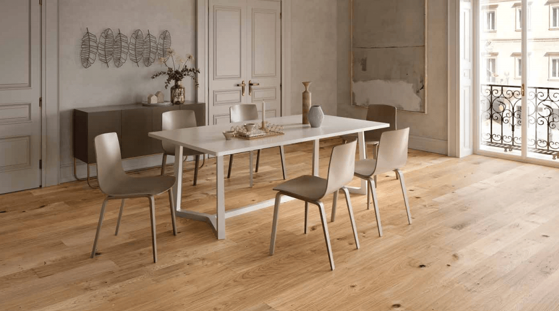 Sala da pranzo minimalista con tavolo in legno, sedie bianche e ampie finestre su un pavimento in legno chiaro.