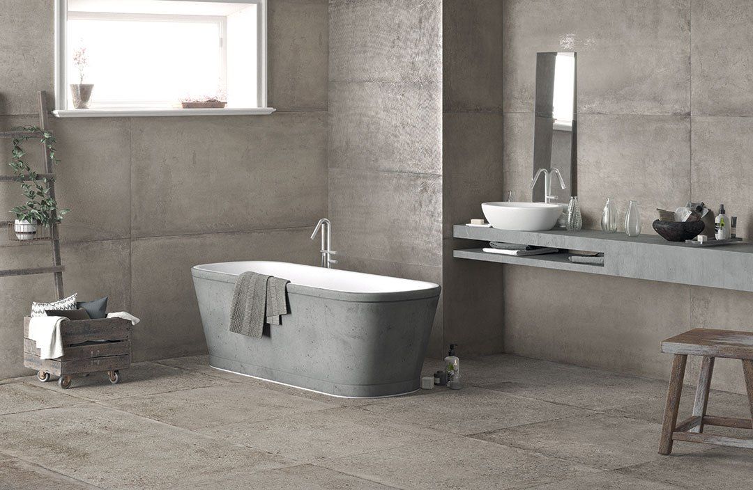 Bagno moderno con vasca freestanding, pareti in pietra, lavabo con mobiletto e sgabello.