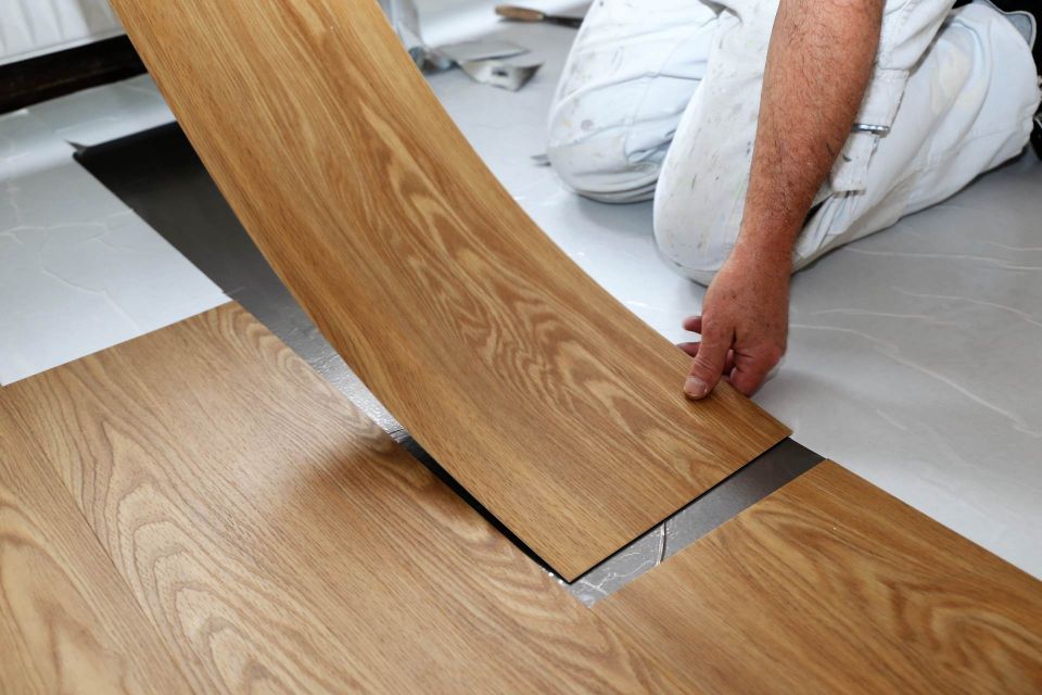 Persona che installa una tavola di legno curva su una giunzione metallica in una stanza