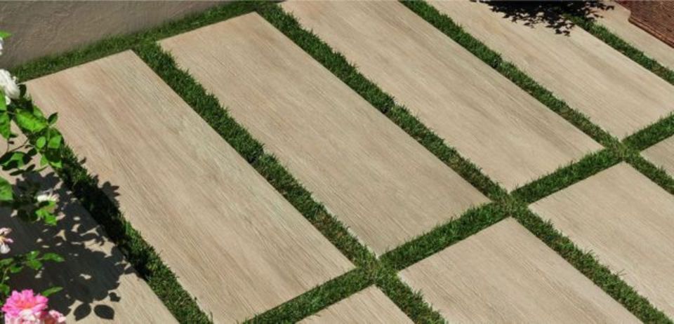 Veduta aerea di campi rettangolari color ocra, separati da sentieri erbosi verdi e fiori colorati ai margini.