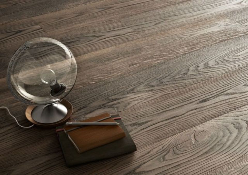 Un piccolo ventilatore da tavolo accanto a uno smartphone e un notebook su un pavimento o un tavolo di legno.