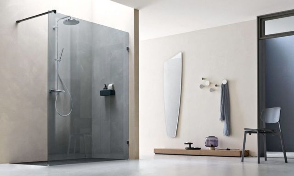 Bagno moderno con box doccia in vetro, specchio a parete, ganci per asciugamani e panca su una parete grigio chiaro.