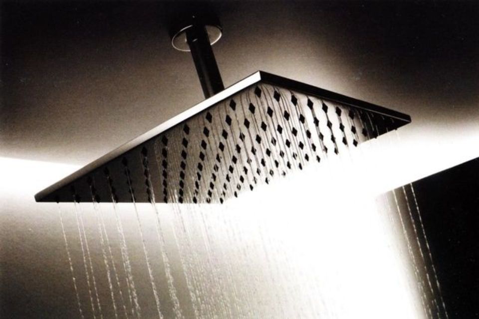 Soffione doccia a pioggia che spruzza acqua da un apparecchio montato a soffitto.