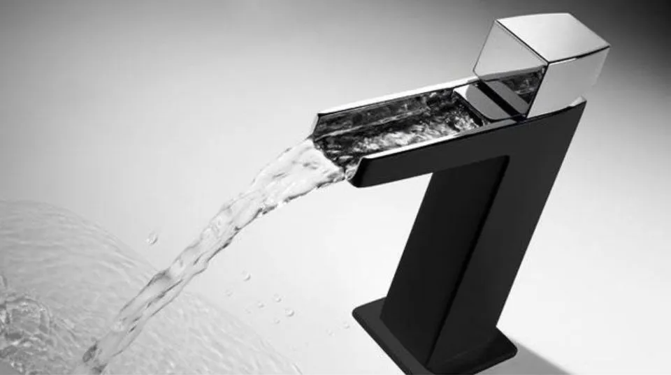 Elegante rubinetto nero moderno che versa acqua in un lavandino su uno sfondo grigio.