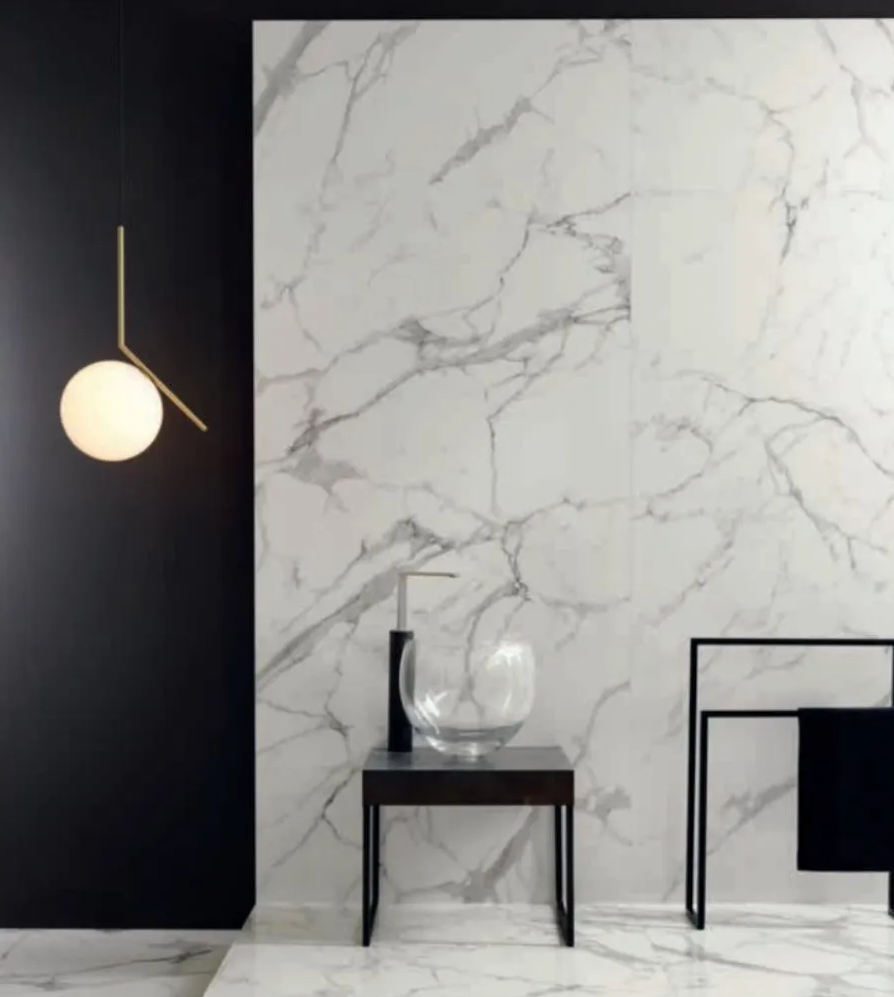 Stanza minimalista con parete scura, pannello in marmo, lampada a sospensione con globo, tavolino e sedia nera.
