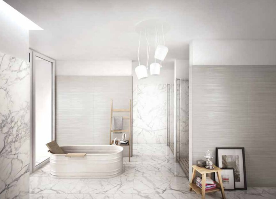 Elegante bagno bianco con piastrelle in marmo, vasca freestanding e luci a sospensione soffuse.
