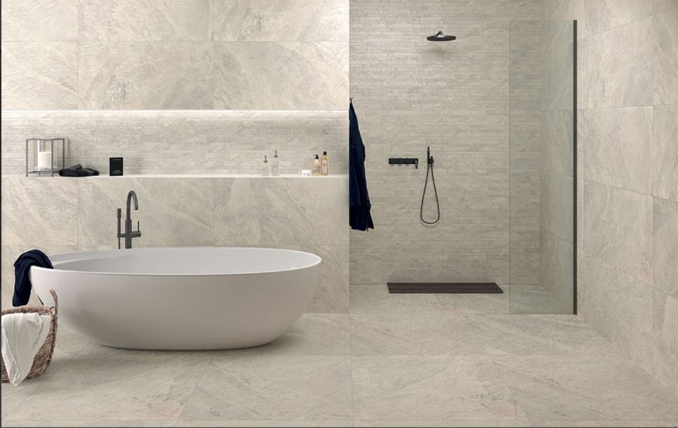 Bagno minimalista sui toni del beige con vasca freestanding, mensola a muro e box doccia in vetro.