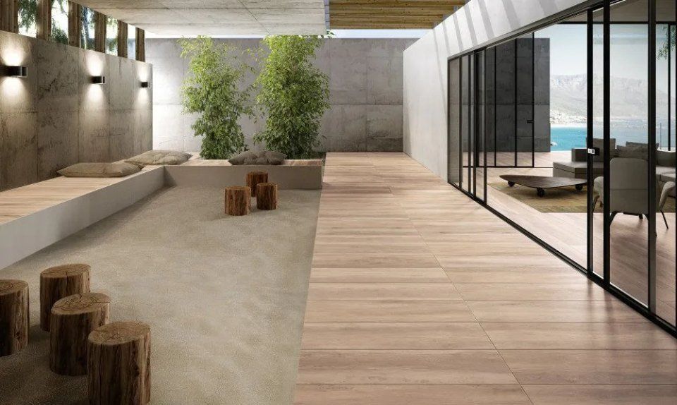 Patio moderno e minimalista con divani, piante in vaso e pareti in vetro con vista sul mare.