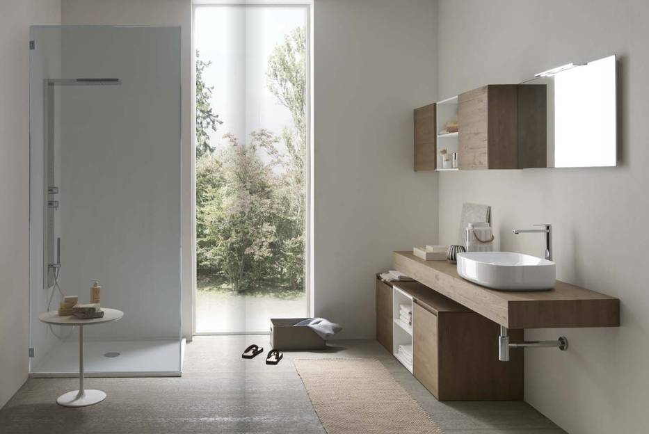 Bagno moderno e minimalista con doccia, lavabo, specchio e ampia finestra con vista sul verde.