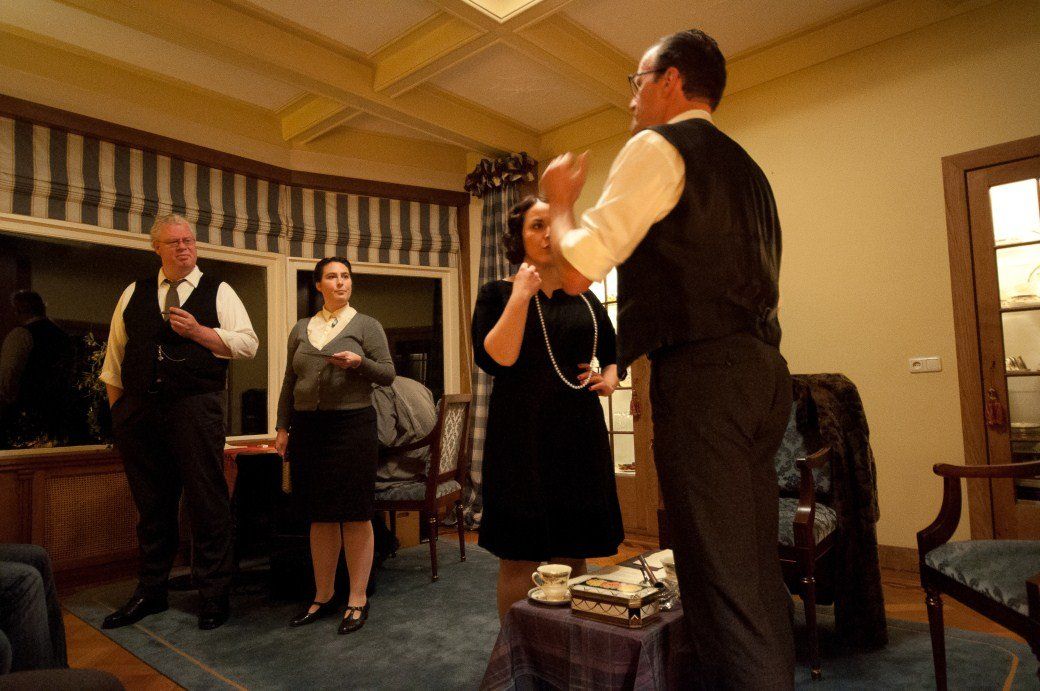 Three people dancing in a warmly lit living room, with two others standing nearby and watching.