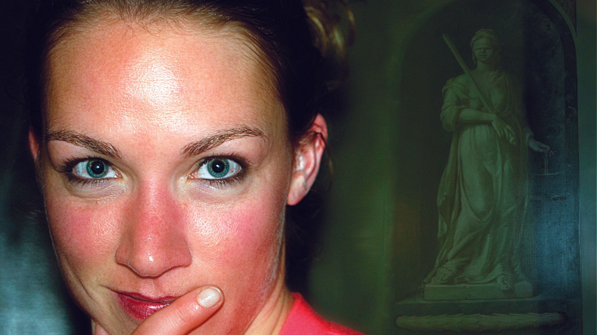 Close-up of a woman with a thoughtful expression against a dark green background with a statue