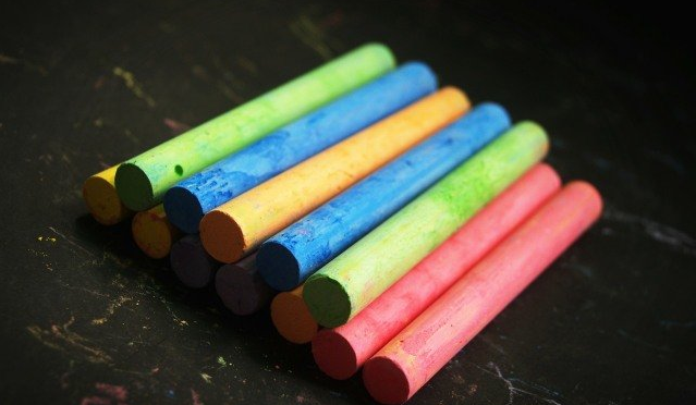Colorful chalk sticks arranged in a layered cluster on a dark surface.