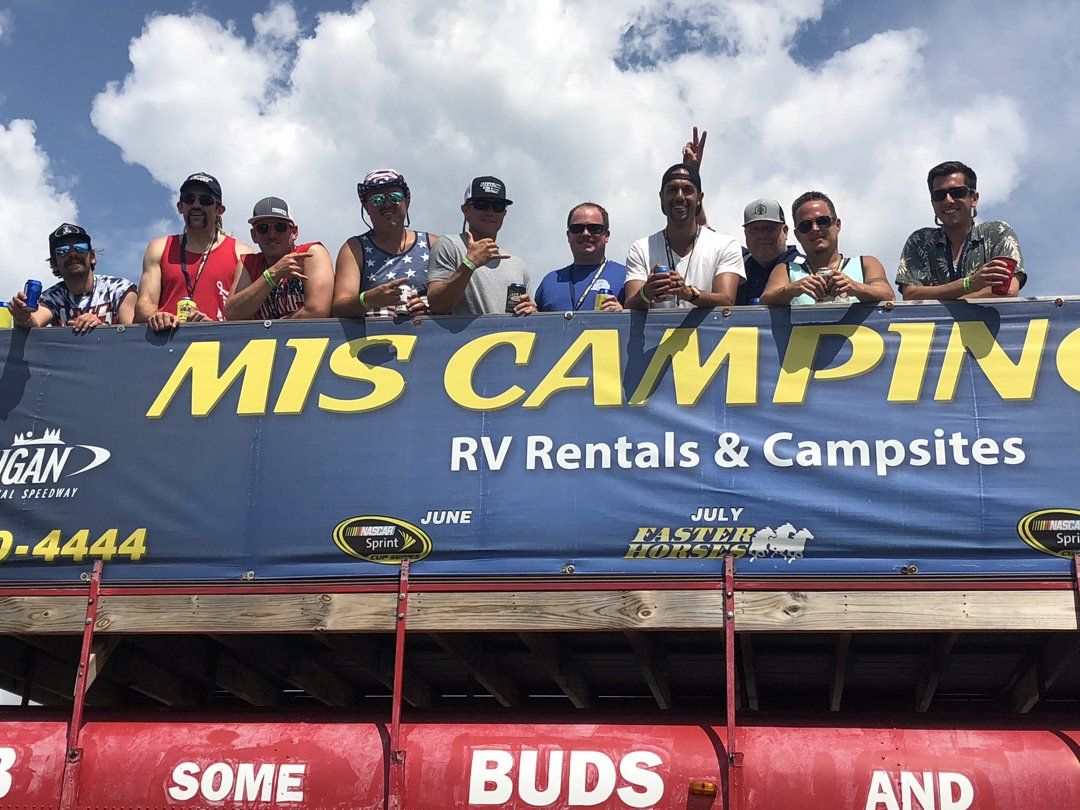 A group of people are standing in front of a mis camping banner.