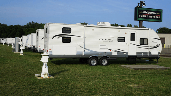 A row of white trailers are parked in a grassy field