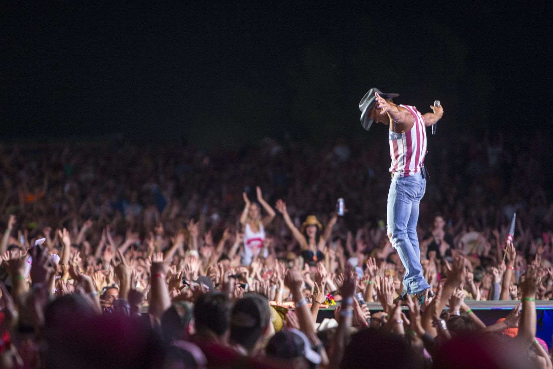A man is standing on a stage in front of a crowd at a concert.
