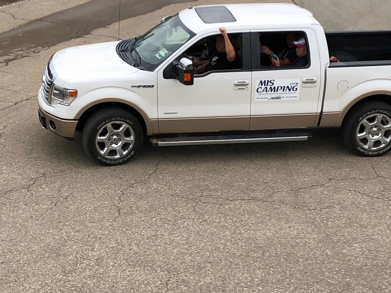 A white pickup truck is driving down a road.
