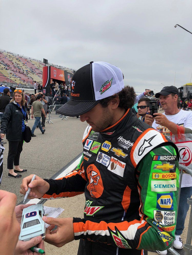 A race car driver is signing autographs for fans