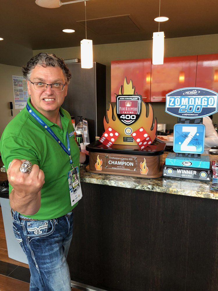 A man in a green shirt is standing in front of a counter holding a ring.