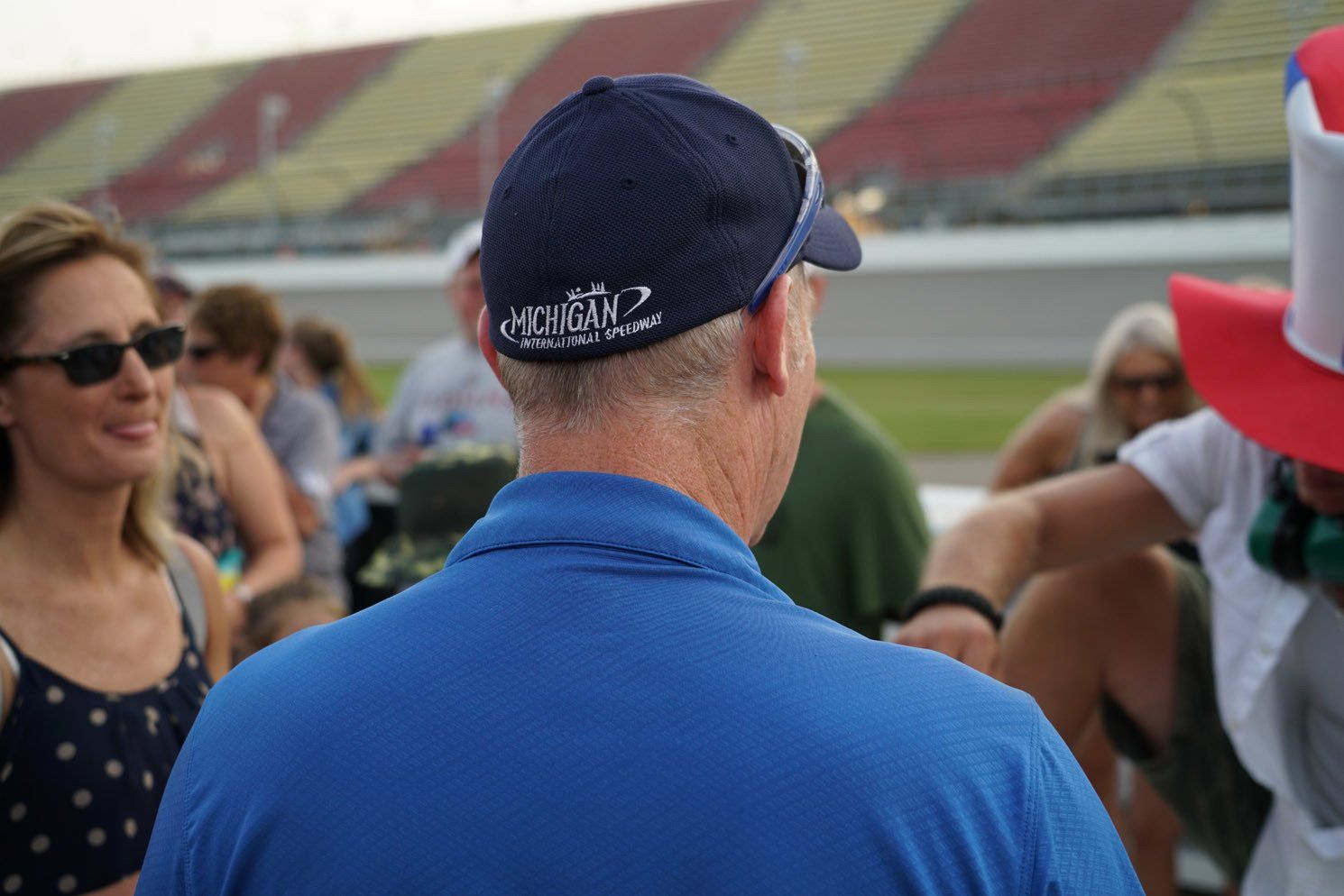 A man wearing a blue shirt and a hat is standing in a crowd of people.
