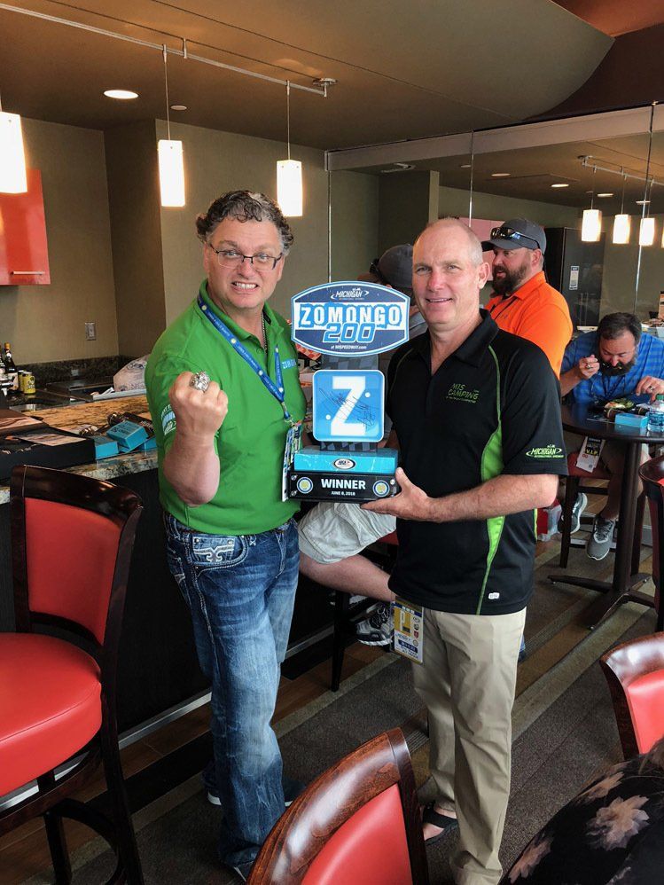 Two men are standing next to each other in a restaurant holding a trophy.