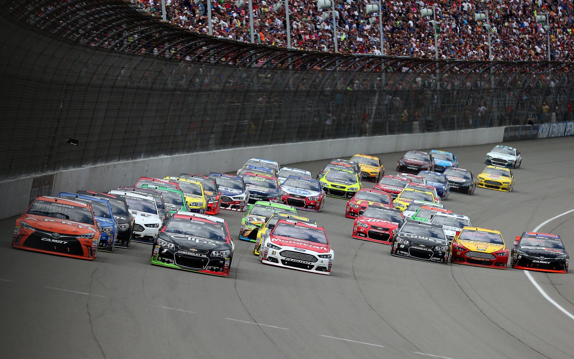 A bunch of cars are racing on a race track.