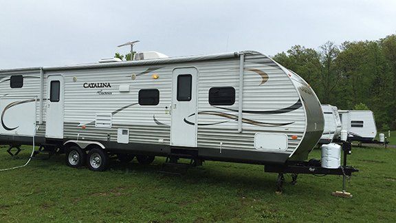 A white trailer is parked in a grassy field.