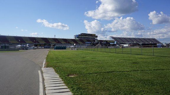 A race track with a lot of grass and a stadium in the background.