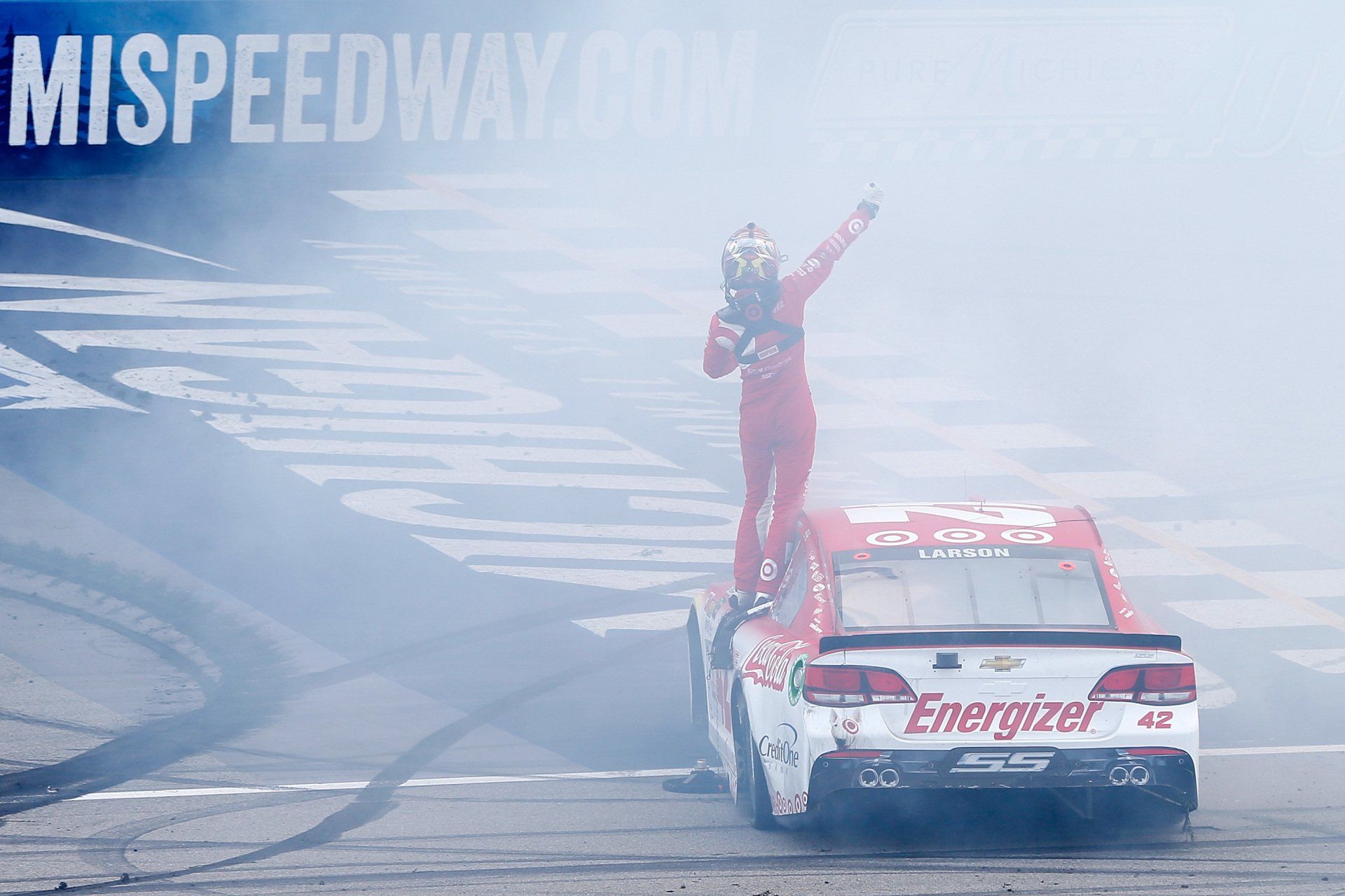 A man is standing on top of a race car.