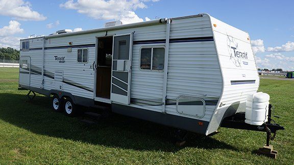 A white trailer is parked in a grassy field.