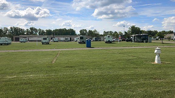 A group of rvs are parked in a grassy field.