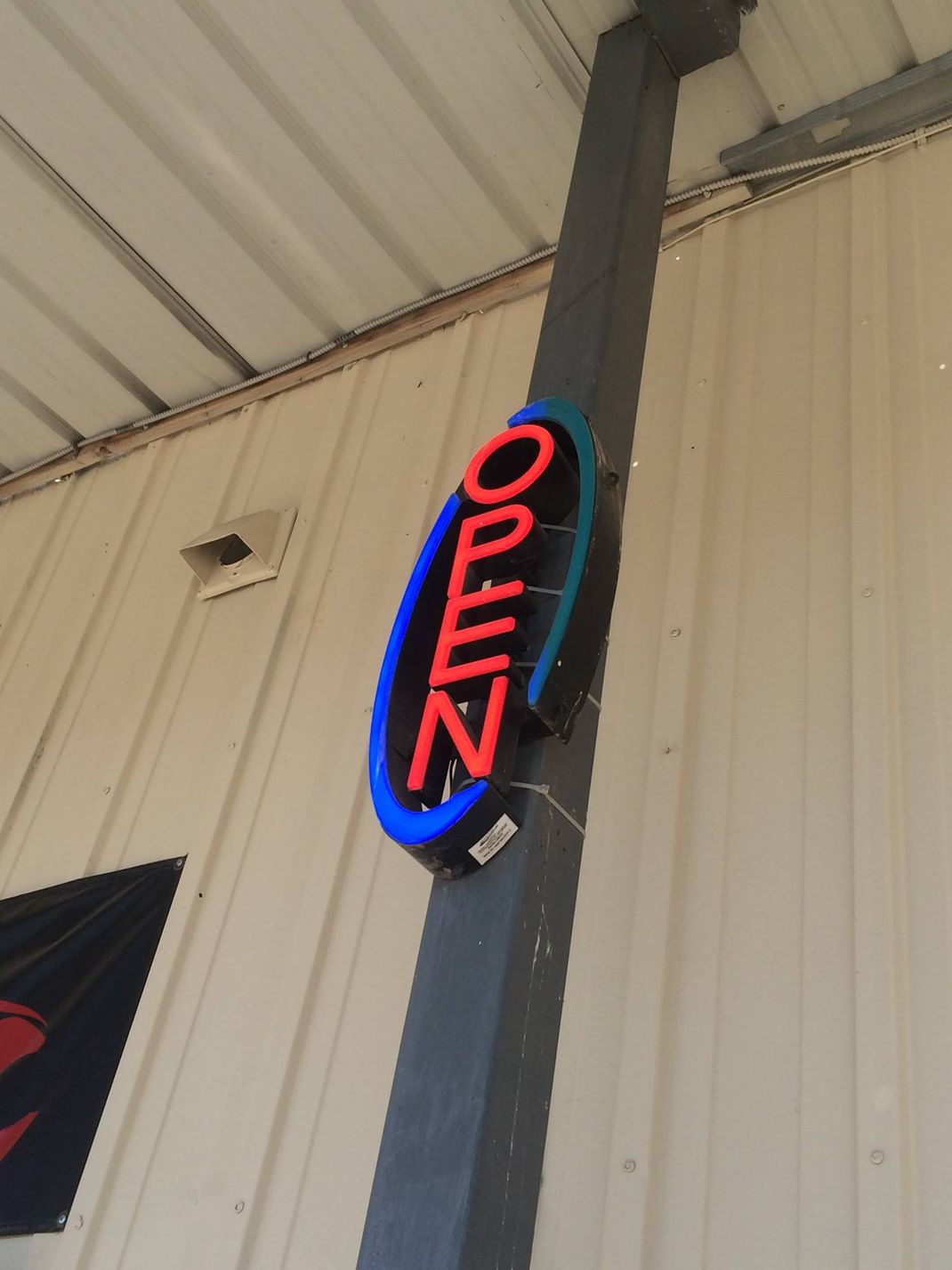 A red and blue open sign hangs on a pole