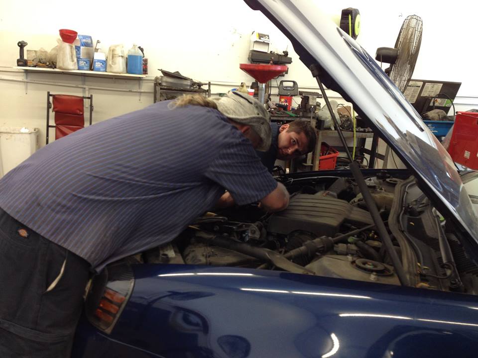 A man is working on a blue car in a garage