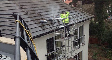 Roof cleaning in progress man pressure cleaning a roof