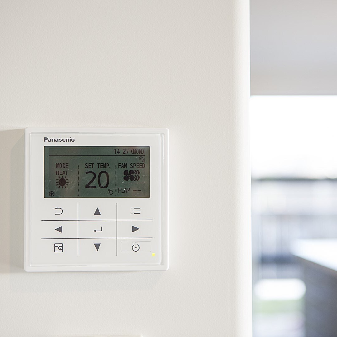 A panasonic thermostat is mounted on a white wall