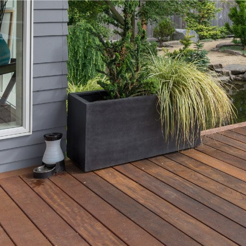 A wooden deck with a large black planter on it