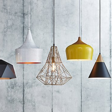 Four different pendant lights are hanging from a concrete wall