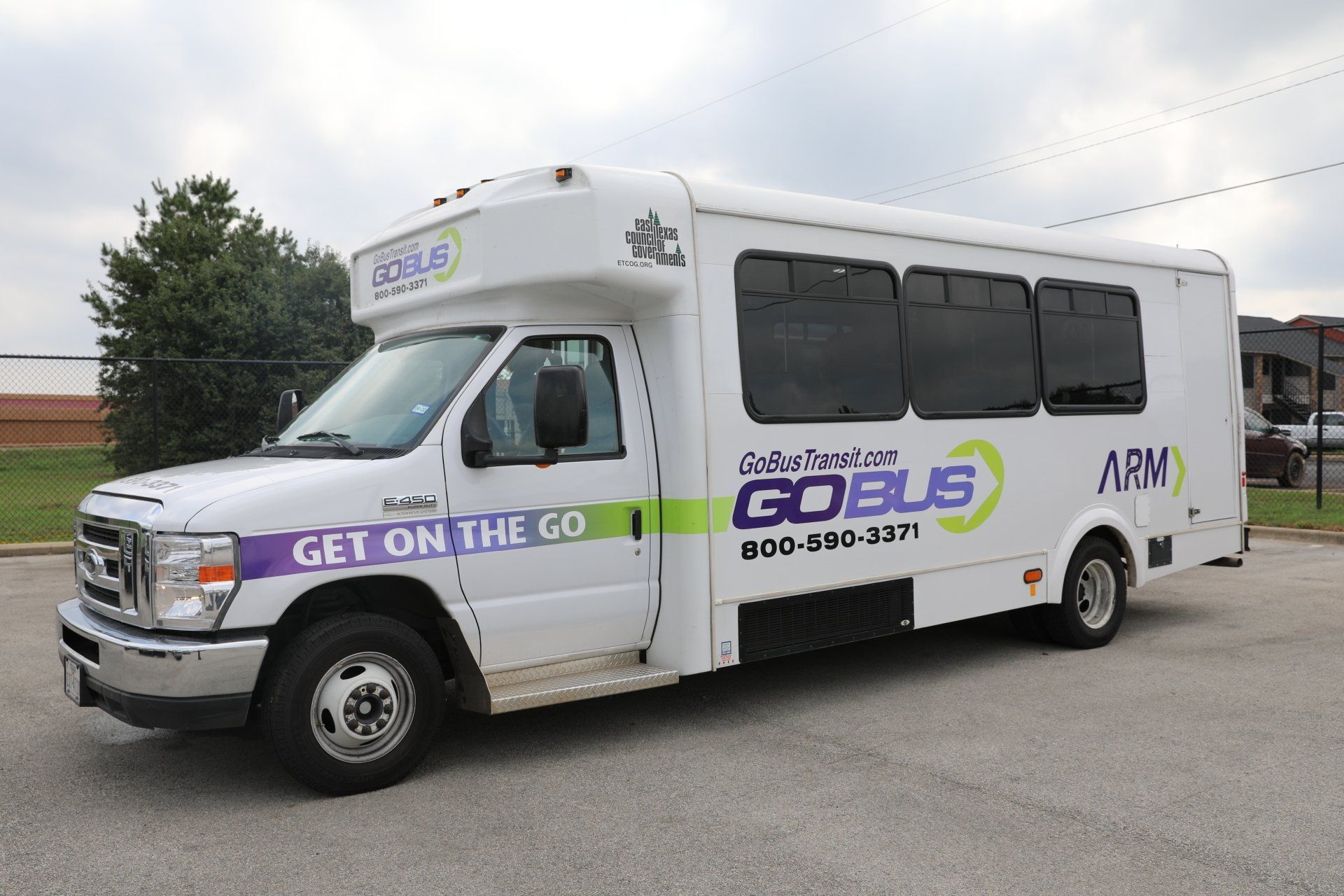 A white go bus is parked in a parking lot
